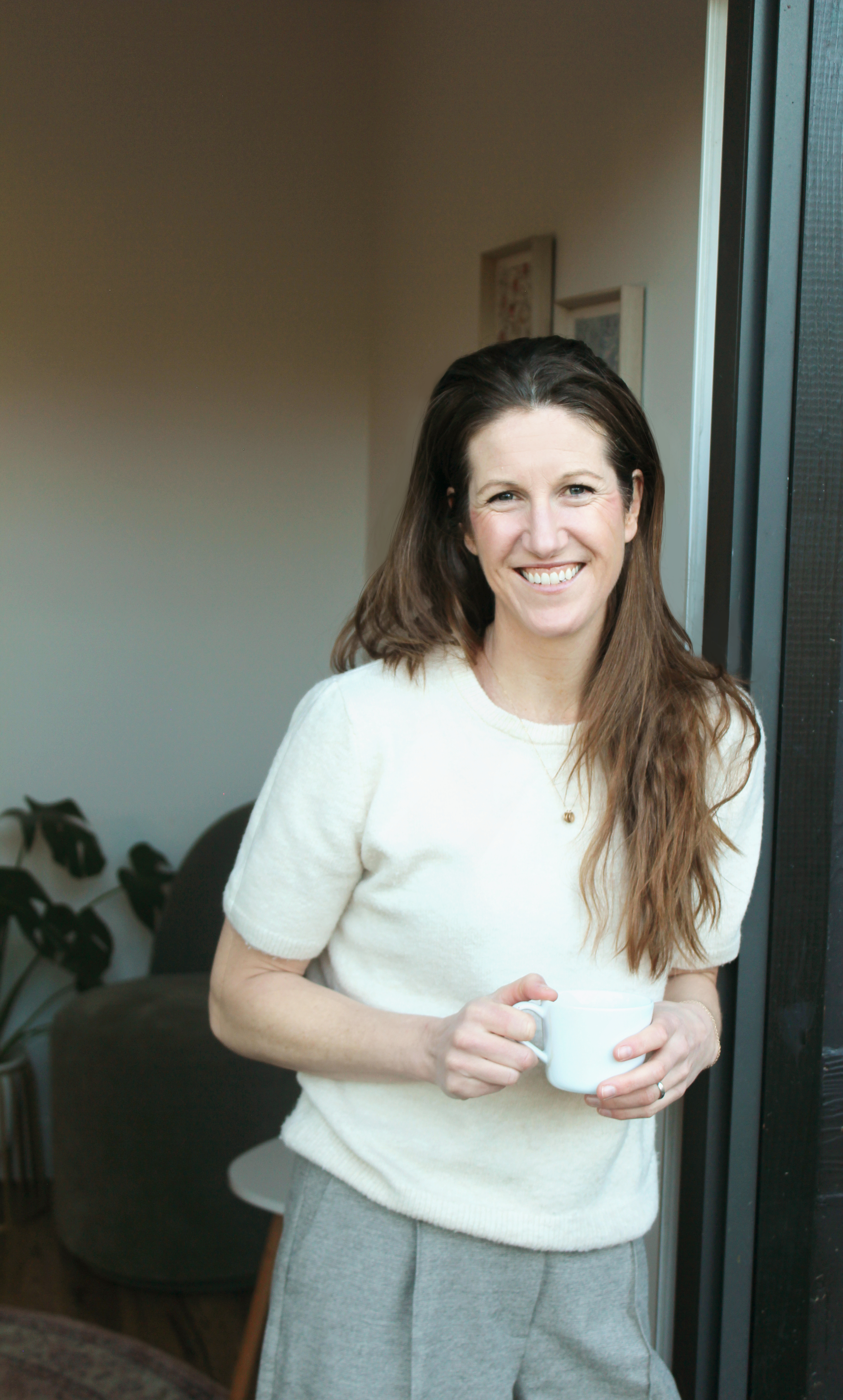 Amy Mills-Guest standing in her counselling office holding a mug